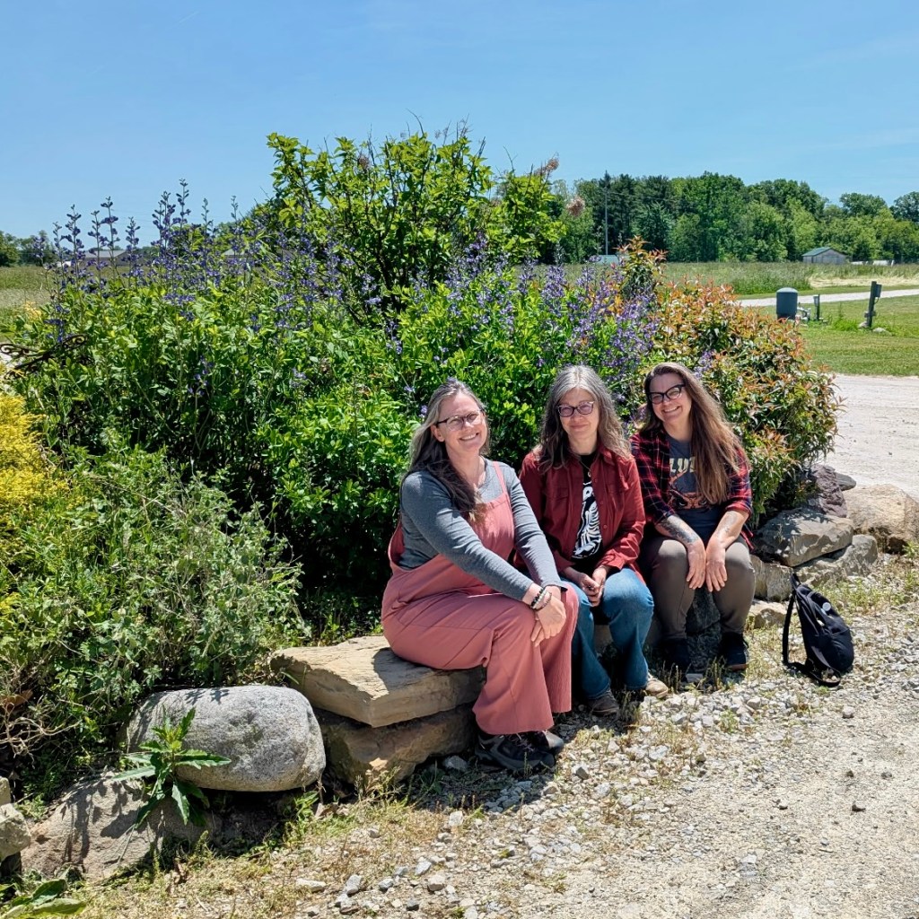 Three of the organizers pose in front of the blooming wild indigo at Bellwether Farm.